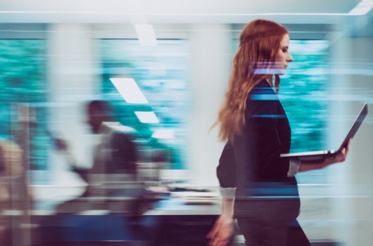 woman with laptop walking in office